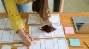 The young designer is sketching a smartphone screen and an app.