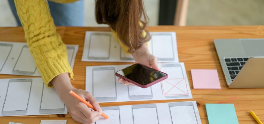 The young designer is sketching a smartphone screen and an app.