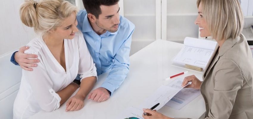 Young married couple sitting with an adviser at desk in a guidance or professional business meeting planning their provision for one's old age.